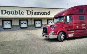 Red Hensley semi truck parked in front of the warehouse dock for Double Diamond